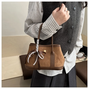 Detail of vintage brown suede handbag with decorative silk ribbon and magnetic closure