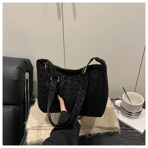 Detail of black leopard print tote bag with gold buckle in a cozy lifestyle setting