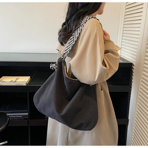 Détail du sac cabas en velours côtelé noir avec bandoulière tissée dans un cadre élégant