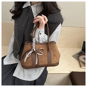 Detail of vintage suede handbag with brown patchwork and white lace bow decoration