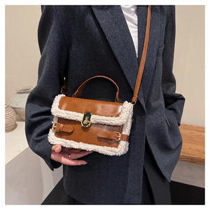 Detail of a brown leather crossbody bag with white faux shearling trim and gold hardware