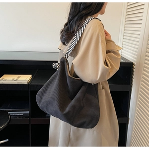 Détail du grand sac cabas en velours côtelé noir avec bandoulière rayée et nœuds