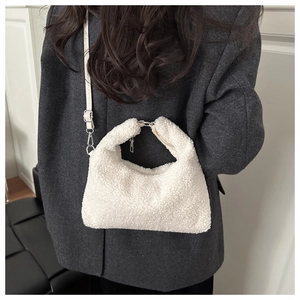Détail d'un sac hobo en peluche blanche avec poignée et bandoulière amovible sur mannequin