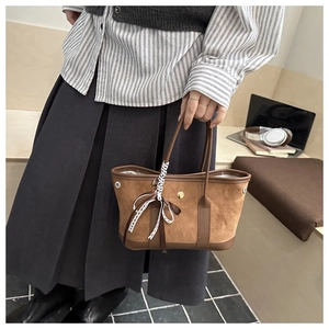 Detailed view of a brown suede vintage tote bag with decorative ribbons and bow