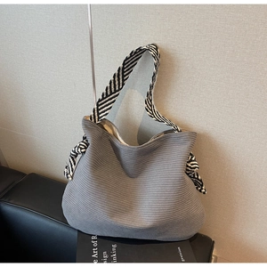 Détail du cabas en velours côtelé gris avec bandoulière tissée à rayures noir et blanc