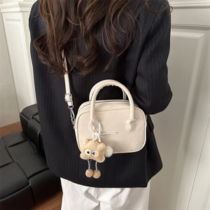 Chic beige crossbody square bag with star plush pendant shown in a fashion outfit setting