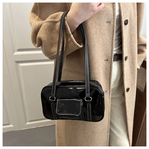 Detail of vintage black patent leather shoulder bag with white contrast stitching and silver hardware