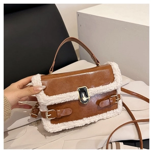 Detailed view of brown leather bag with white faux fur trim and golden turn-lock closure