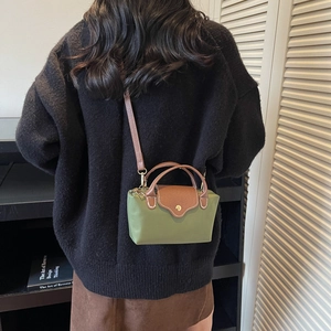Green nylon handbag with brown leather flap and detachable shoulder strap on person