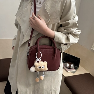 Bordeaux red crossbody bag with cute teddy bear charm on minimalist trench coat style