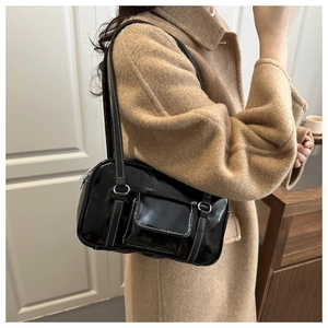 Detail of retro black patent leather shoulder bag with white contrast stitching and silver buckle