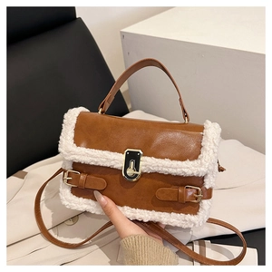 Detail of brown leather bag with white faux fur trim and gold metal buckle lock