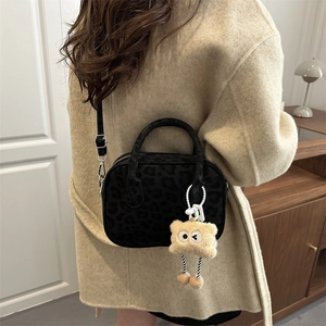 Fashionable leopard print square shoulder bag with plush charm on a beige coat model