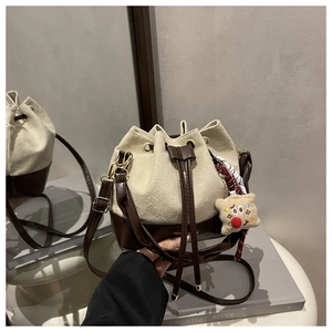 Detail of a retro color-block bucket bag with cream fabric and brown leather textures