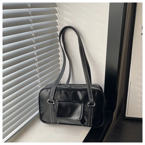 Detail of black glossy leather shoulder bag with white contrast stitching and silver rings
