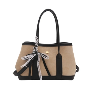 Chic beige suede tote with black leather trim and lace ribbon detail on white background