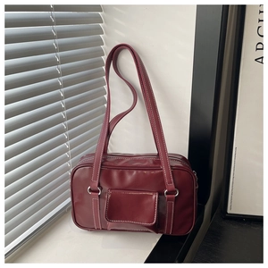 Detail of burgundy leather square bag with white contrast stitching and front pocket
