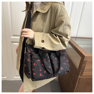 Detail view of large cherry print nylon bag showing multiple functional zipper pockets