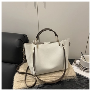 Dettaglio della borsa tote beige in pelle martellata con manici marroni e finiture dorate
