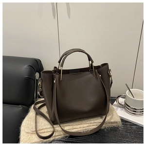 Dettaglio borsa tote in pelle marrone scuro con rivetti su una coperta morbida