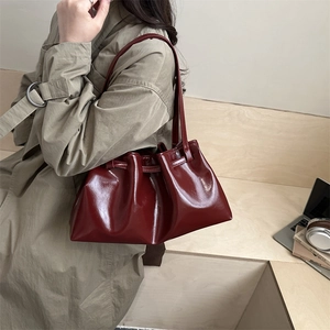 Glossy burgundy leather tote bag for women shown with a khaki trench coat for city style