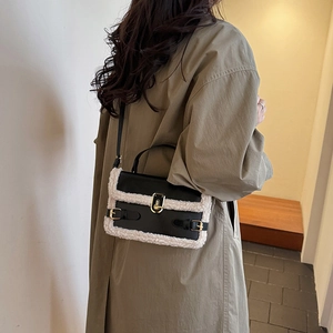 Minimalist black faux leather and white shearling shoulder bag with a gold twist lock