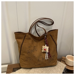 Detail einer braunen Wildleder-Tote-Bag mit handgezeichneten Graffiti und Plüschanhänger