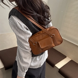 Minimalist caramel brown square underarm bag with white stitching shown on model