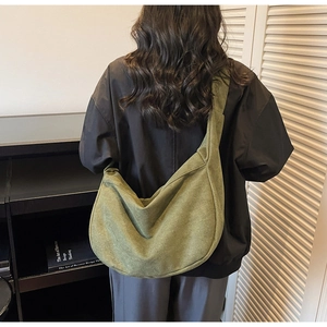 Olive green canvas hobo bag on shoulder showing large capacity and half-moon design