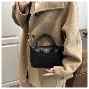 Detail view of black leopard print mini tote with leather handles and crossbody strap