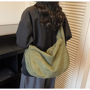 Close-up of army green large canvas crossbody bag worn by model in a minimalist room