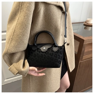 Detail of black leopard print leather crossbody bag with silver hardware and strap