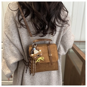 Brown suede crossbody bag detail showing vintage texture and plush bear charm