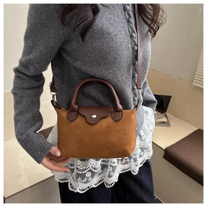 Detail of a brown suede mini crossbody bag with leather trim on a grey knit cardigan