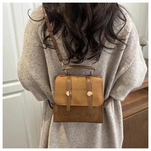 Detail of vintage caramel brown crossbody bag with embossed logo and metal buckles