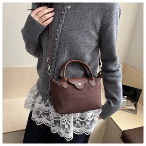 Detail showing the matte dark brown leather texture and silver buckle of the handbag