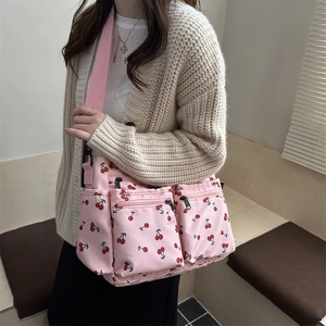 Pink tote bag with cherry print and multi-pocket design shown on female model