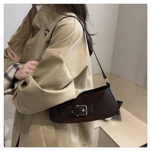 Detail of vintage brown suede and leather shoulder bag with silver buckle on a trench coat