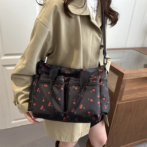 Minimalist black nylon tote bag with red cherry print and multiple zipper pockets