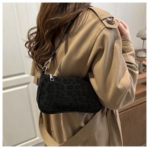 Detail of black leopard print baguette bag on model wearing a beige trench coat