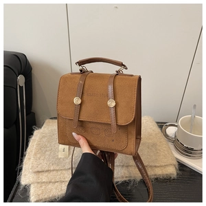 Detail of a brown suede backpack featuring minimalist bear prints and gold metal buckles