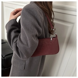 Detail of dark burgundy suede baguette bag with silver hardware on a grey tweed blazer