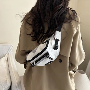 Sac de poitrine minimaliste en nylon blanc avec sangle réglable porté sur un trench-coat