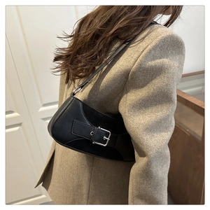 Detalle del bolso de hombro negro minimalista con hebilla metálica en una modelo