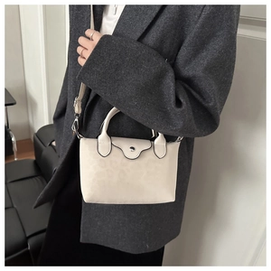 Mini off-white crossbody dumpling bag with subtle leopard print on model in grey blazer