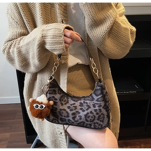 Dettaglio borsa leopardata con tracolla a catena dorata e ciondolo bambola di peluche