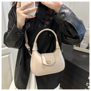 Detail of creamy white crescent shoulder bag in glossy patent leather with gold buckle