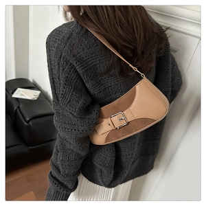 Detalle de un bolso de hombro vintage bicolor con hebilla metálica llevado por una modelo