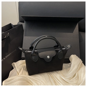 Detailed view of a mini black nylon tote bag on white fabric with premium gift packaging