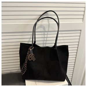 Detail of black suede tote bag featuring a vintage bronze C-letter charm and dual straps